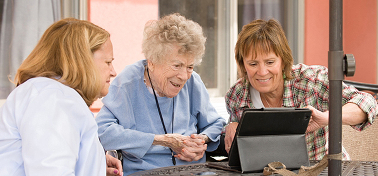 subacute rehab from crouse community center image of elderly patient family member and nurse looking at tablet on table