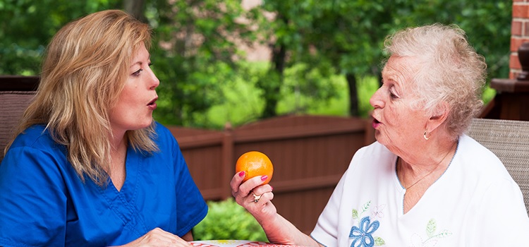 elderly rehabilitation centers image of speech therapist and elderly patient holding orange at crouse community center